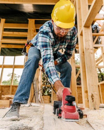 trabajador con casco lijando una pieza de madera